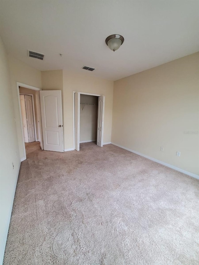 unfurnished bedroom featuring light colored carpet and a closet