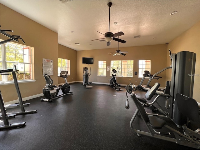 gym with ceiling fan, a textured ceiling, and a wealth of natural light