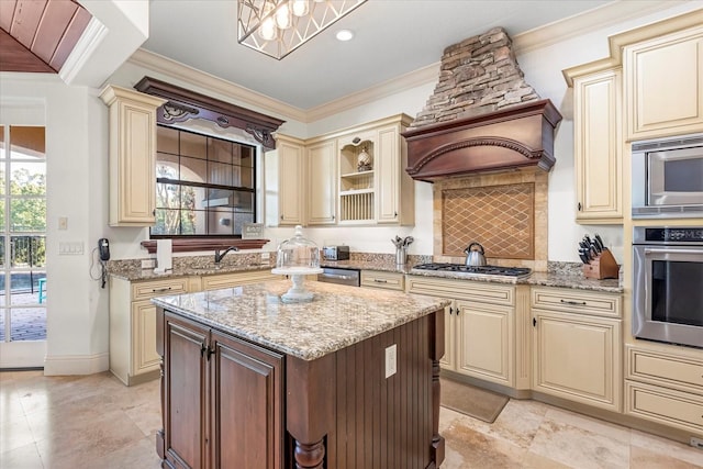 kitchen featuring a center island, light stone counters, stainless steel appliances, and cream cabinets