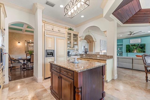 kitchen with cream cabinets, a center island, coffered ceiling, decorative light fixtures, and ornamental molding