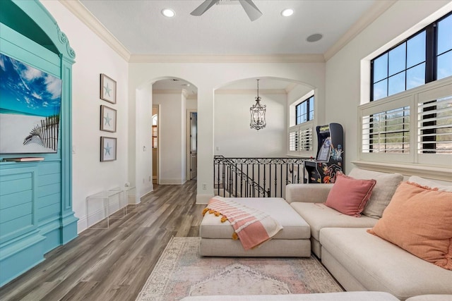 living room with light hardwood / wood-style floors, crown molding, and ceiling fan with notable chandelier