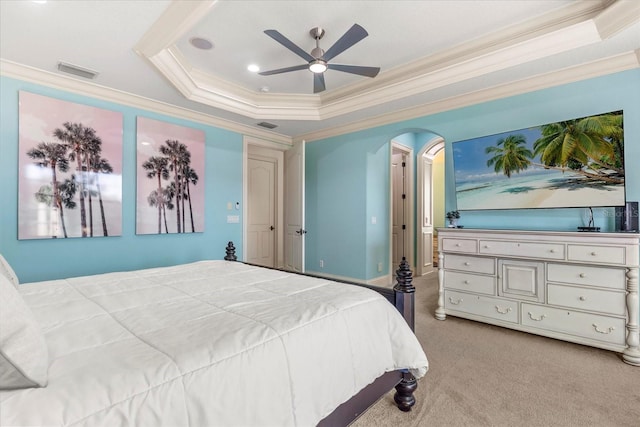 carpeted bedroom with ornamental molding, a tray ceiling, and ceiling fan