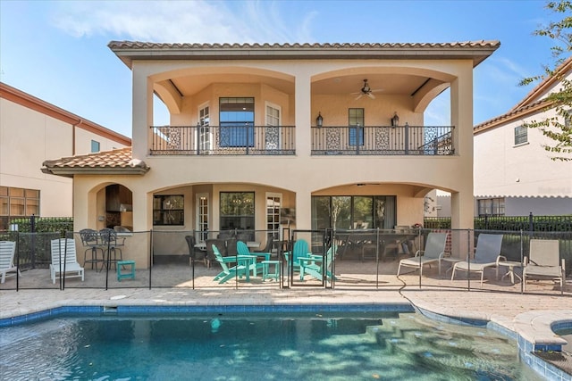 back of property featuring a balcony, a patio area, a fenced in pool, and ceiling fan