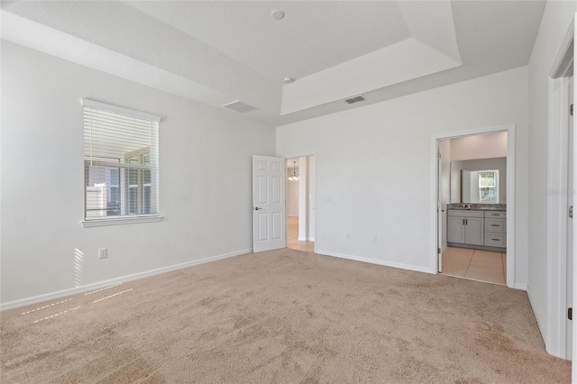 carpeted empty room featuring a tray ceiling