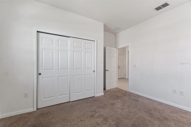 unfurnished bedroom with a closet and light colored carpet