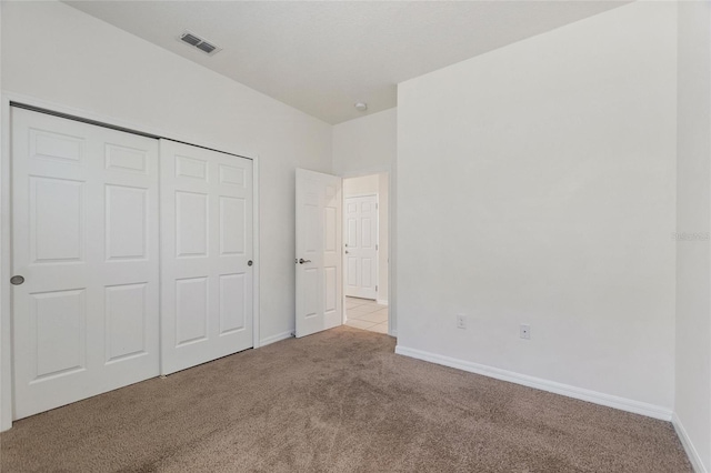 unfurnished bedroom featuring light carpet and a closet