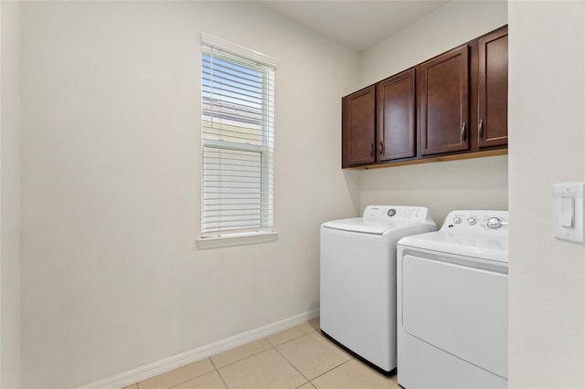 clothes washing area featuring washer and dryer, light tile patterned floors, and cabinets