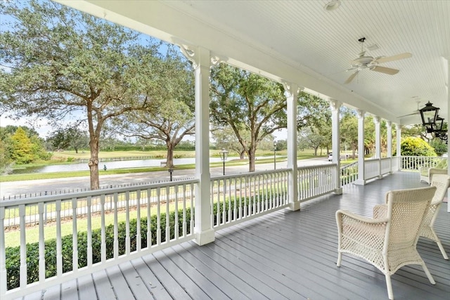 wooden terrace featuring a porch, a lawn, a water view, and ceiling fan