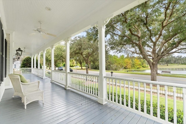 deck with covered porch, a yard, a water view, and ceiling fan