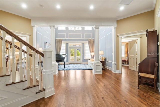 foyer with french doors, crown molding, wood-type flooring, and ornate columns