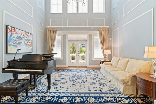 sitting room featuring hardwood / wood-style floors, french doors, and a towering ceiling