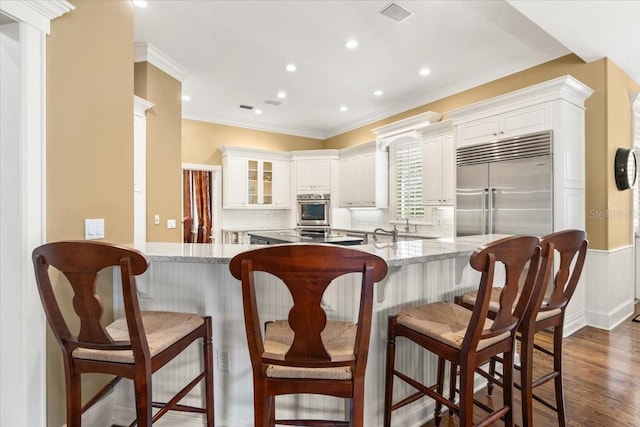 kitchen with kitchen peninsula, white cabinetry, stainless steel appliances, and dark wood-type flooring