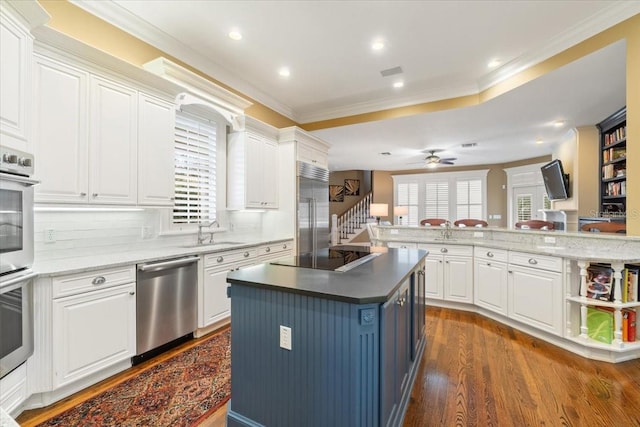 kitchen with appliances with stainless steel finishes, dark hardwood / wood-style flooring, a kitchen island, and white cabinets