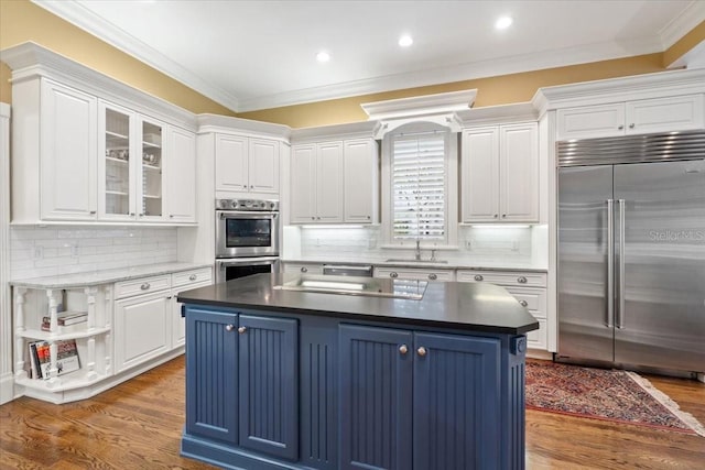 kitchen with blue cabinets, crown molding, appliances with stainless steel finishes, and dark hardwood / wood-style floors