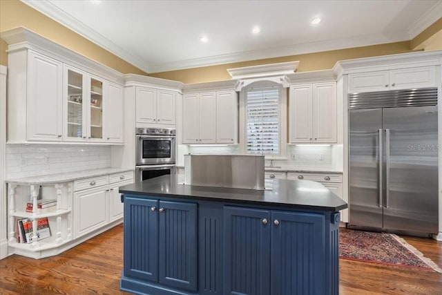 kitchen with blue cabinetry, stainless steel appliances, ornamental molding, and a kitchen island