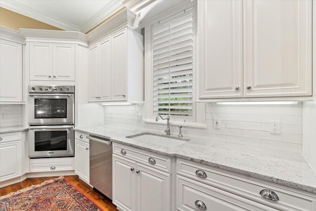 kitchen with stainless steel appliances, sink, light stone countertops, white cabinetry, and dark hardwood / wood-style flooring