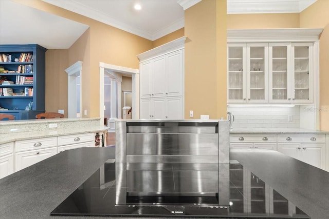 kitchen featuring ornamental molding, white cabinets, light stone counters, and backsplash