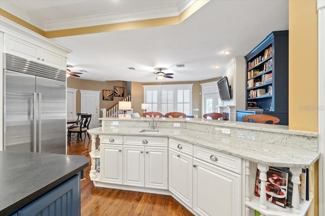 kitchen with crown molding, light hardwood / wood-style floors, stainless steel built in refrigerator, and white cabinets