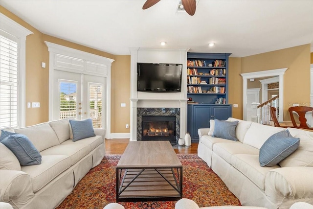 living room featuring ceiling fan, wood-type flooring, and a high end fireplace