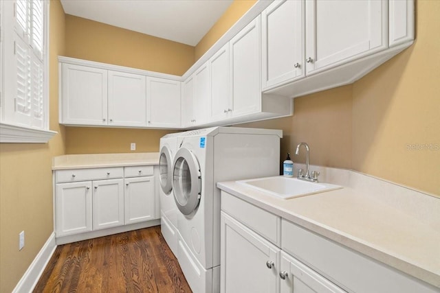 clothes washing area with cabinets, washer and dryer, sink, and dark hardwood / wood-style floors