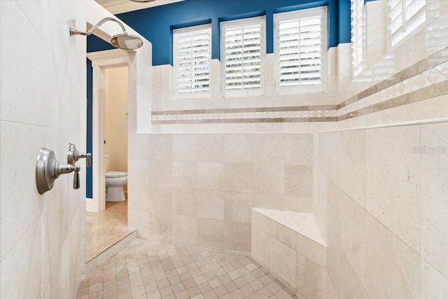 bathroom featuring toilet, tile patterned floors, and tiled shower