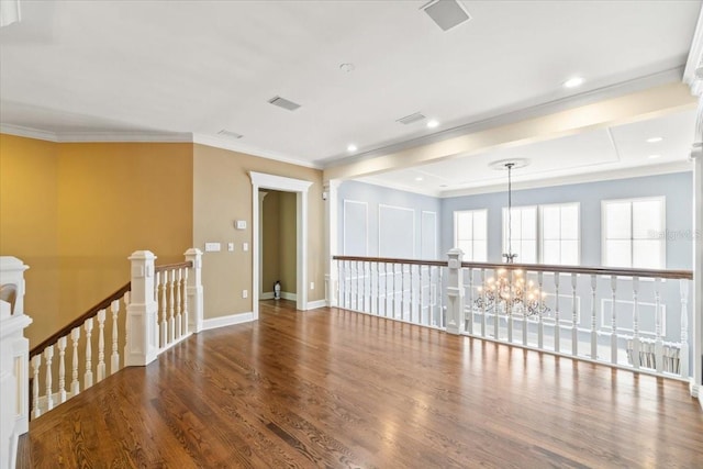 spare room with crown molding, wood-type flooring, and a chandelier