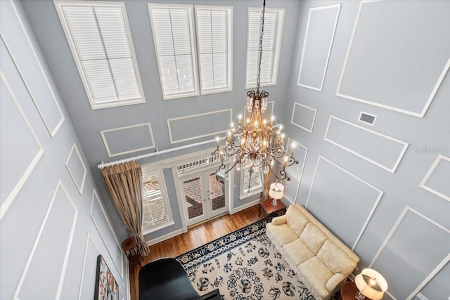 details with french doors, hardwood / wood-style flooring, and an inviting chandelier