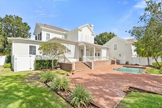 rear view of house featuring a yard, a patio, and a fenced in pool