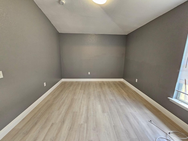 additional living space with vaulted ceiling and light hardwood / wood-style flooring