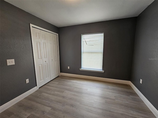 unfurnished bedroom with a closet and light hardwood / wood-style flooring