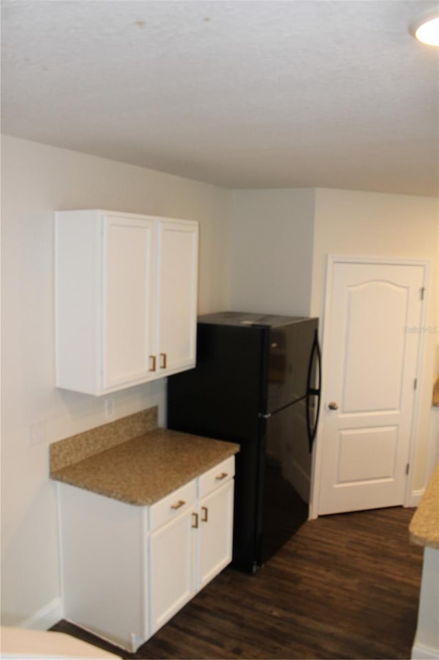 kitchen featuring black fridge, white cabinets, and dark hardwood / wood-style floors