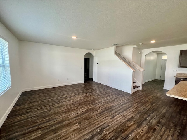 unfurnished living room with a textured ceiling and dark hardwood / wood-style floors