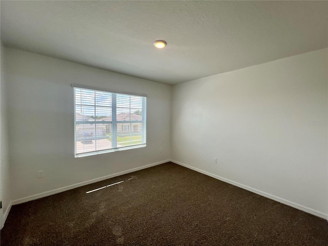 spare room featuring dark carpet