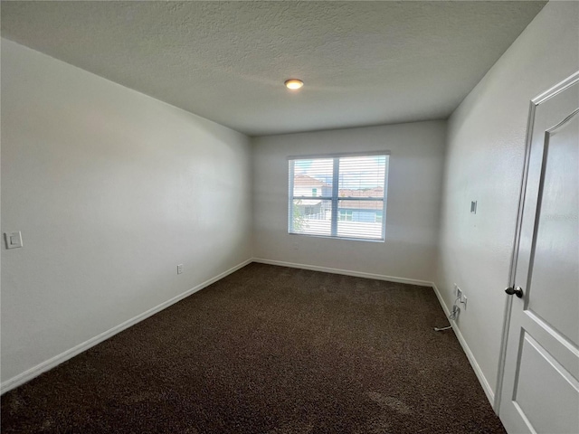 unfurnished room featuring a textured ceiling and dark colored carpet