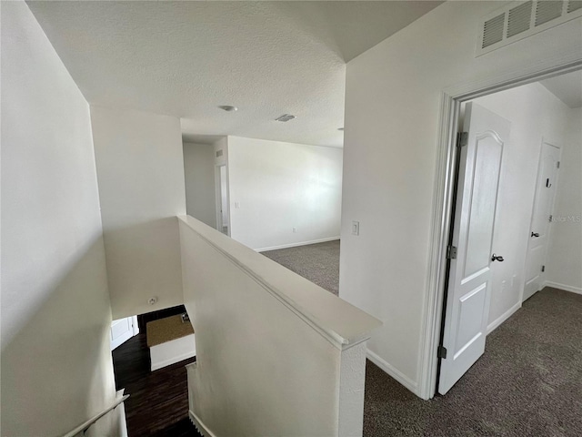 stairway with carpet flooring and a textured ceiling