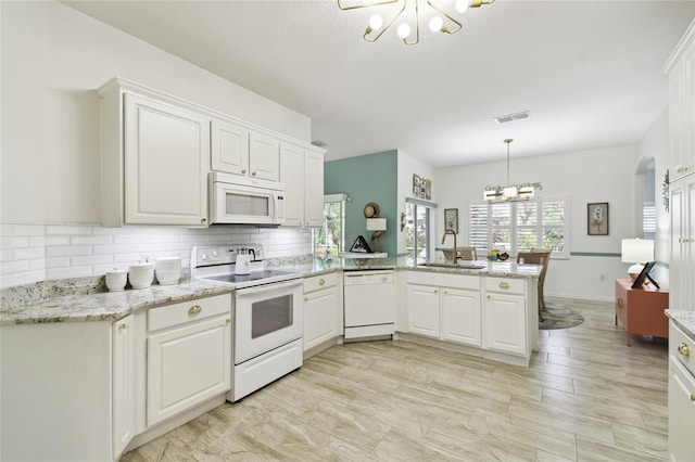 kitchen with kitchen peninsula, white appliances, white cabinets, and sink