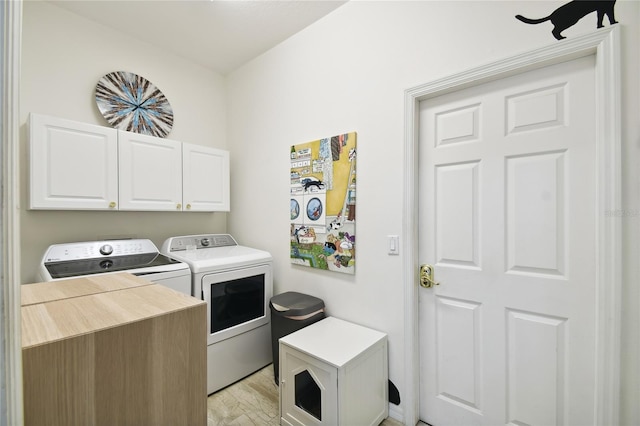 laundry room with cabinets, washing machine and dryer, and light hardwood / wood-style flooring