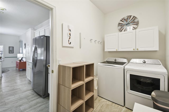 laundry area with cabinets, light hardwood / wood-style floors, and washer and clothes dryer