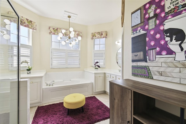 bathroom with tile patterned flooring, a chandelier, plenty of natural light, and a tub