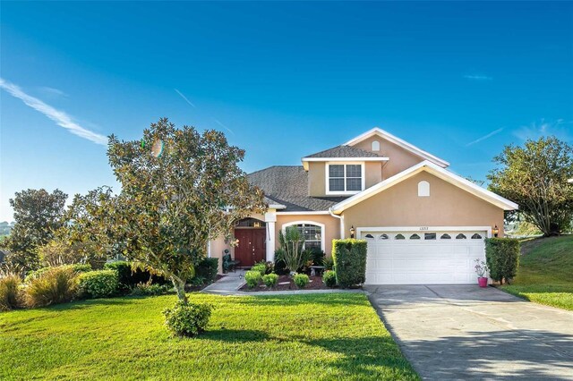 12213 Still Meadow Dr, Clermont, FL 34711 - traditional-style house with stucco siding, a front yard, an attached garage, and concrete driveway
