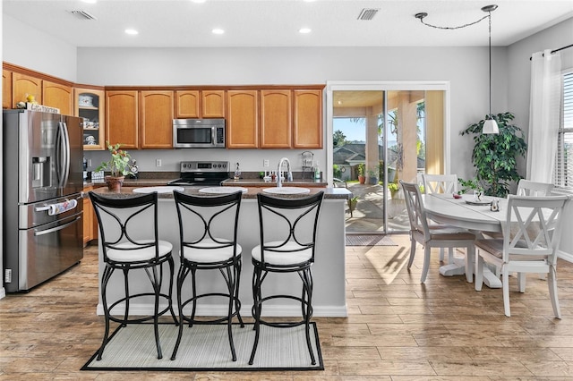 12213 Still Meadow Dr, Clermont, FL 34711 - kitchen with stainless steel appliances, brown cabinets, dark countertops, glass insert cabinets, and a kitchen breakfast bar