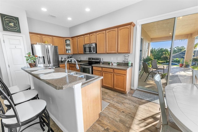 12213 Still Meadow Dr, Clermont, FL 34711 - kitchen with appliances with stainless steel finishes, light wood-style flooring, glass insert cabinets, recessed lighting, and a kitchen island with sink