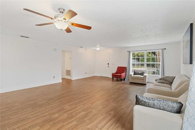 living room featuring ceiling fan, a textured ceiling, and light wood-type flooring