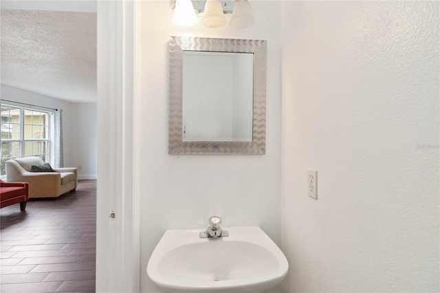 bathroom featuring sink, an inviting chandelier, a textured ceiling, and hardwood / wood-style flooring