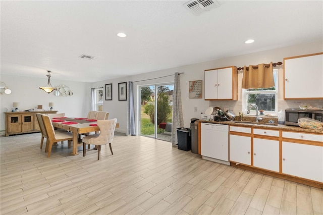 kitchen with pendant lighting, white dishwasher, white cabinets, sink, and light hardwood / wood-style flooring