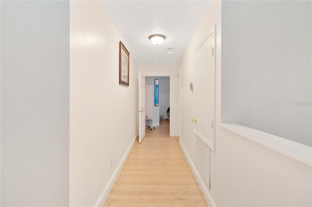 hall with a textured ceiling and light hardwood / wood-style flooring