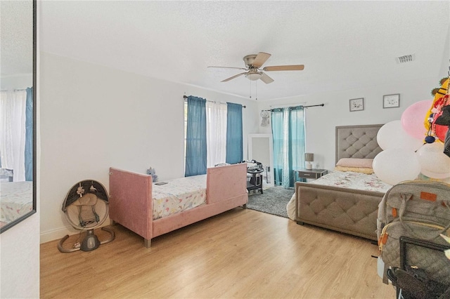 bedroom with ceiling fan, light wood-type flooring, and a textured ceiling