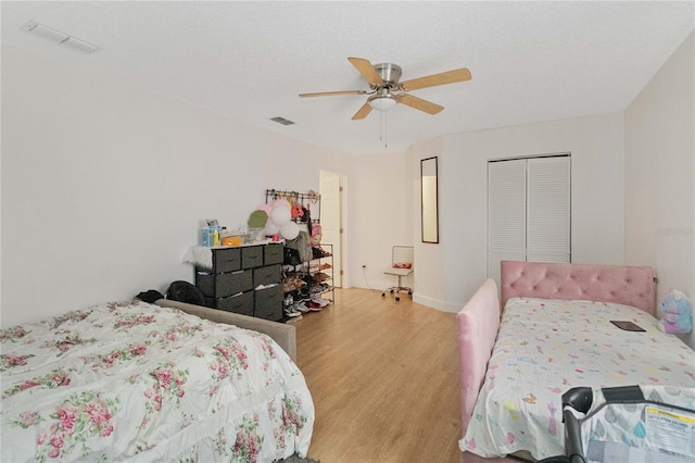 bedroom with ceiling fan, light wood-type flooring, a textured ceiling, and a closet