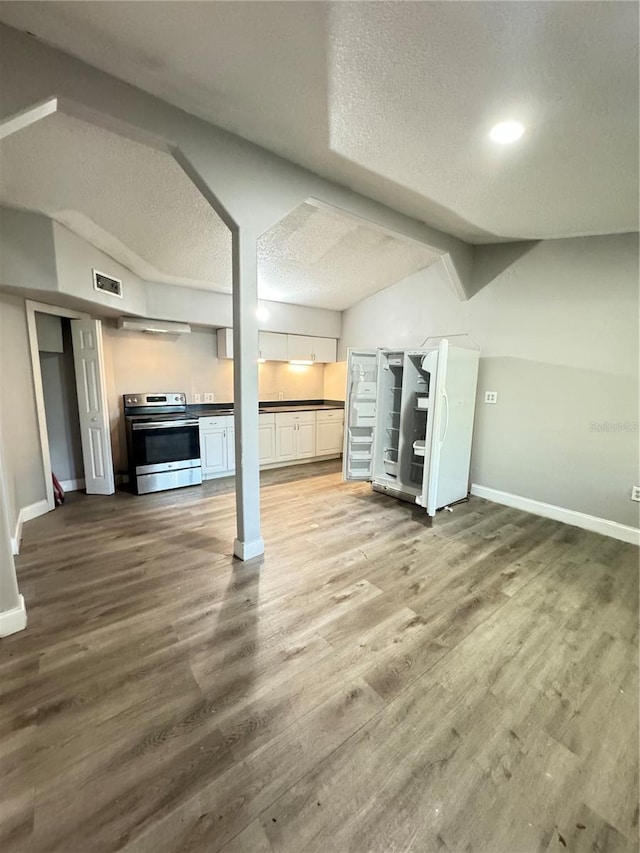 unfurnished living room with hardwood / wood-style flooring, a textured ceiling, and vaulted ceiling with beams