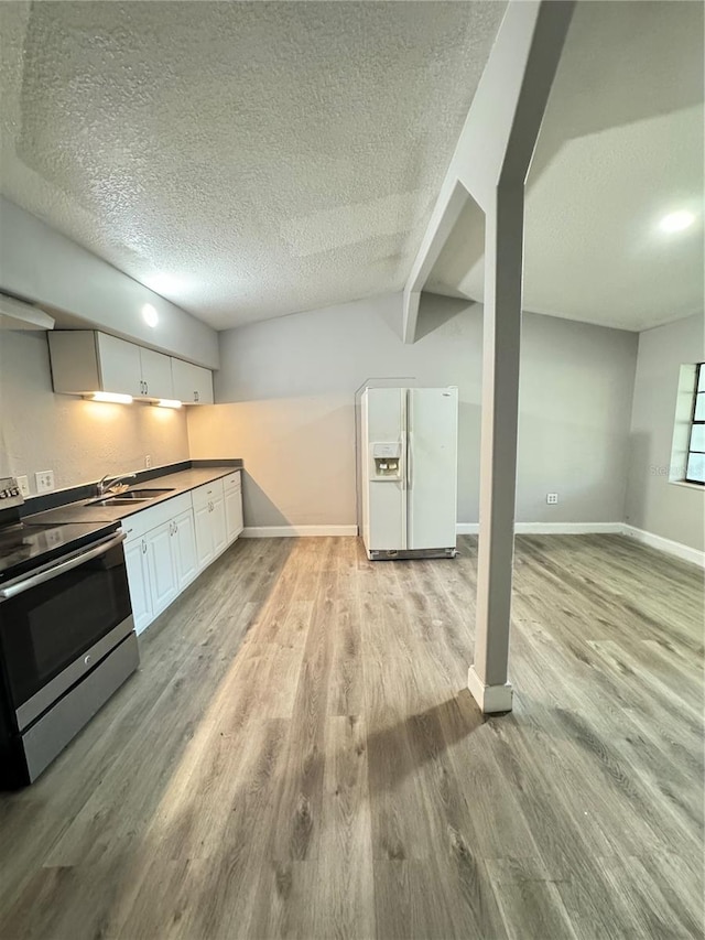 kitchen with white fridge with ice dispenser, stainless steel range, light hardwood / wood-style flooring, white cabinets, and a textured ceiling